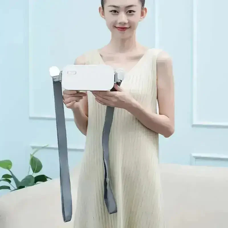 Woman holding a white massage device with gray straps in a modern living room setting