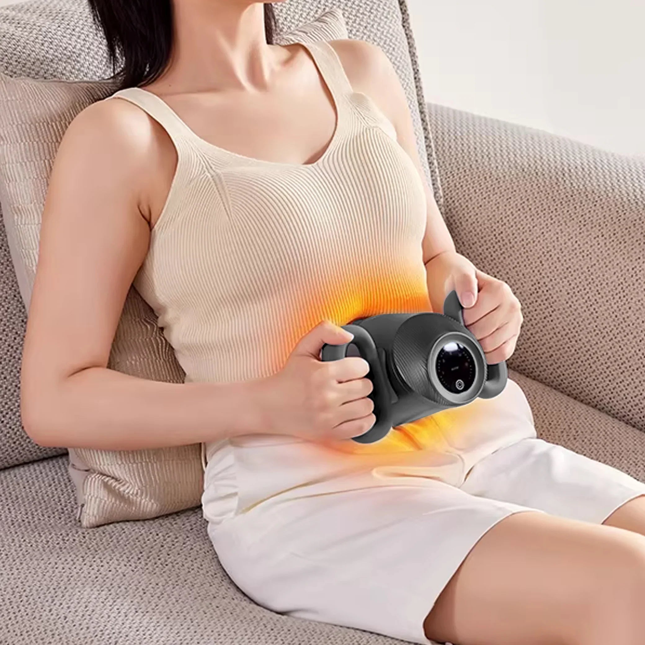 Woman relaxing on couch using a portable abdominal massager with heat therapy