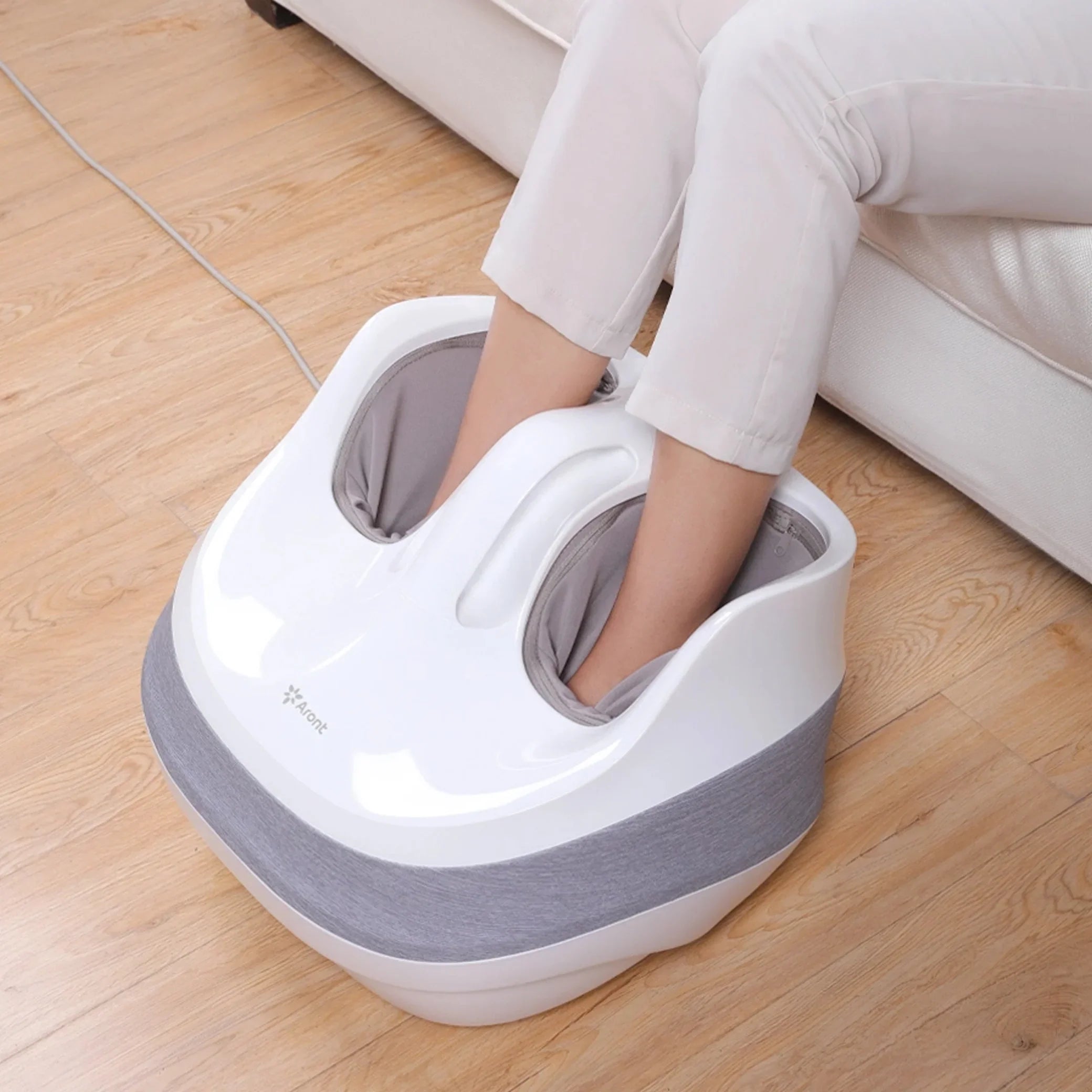White and gray foot massager with person using it on wooden floor