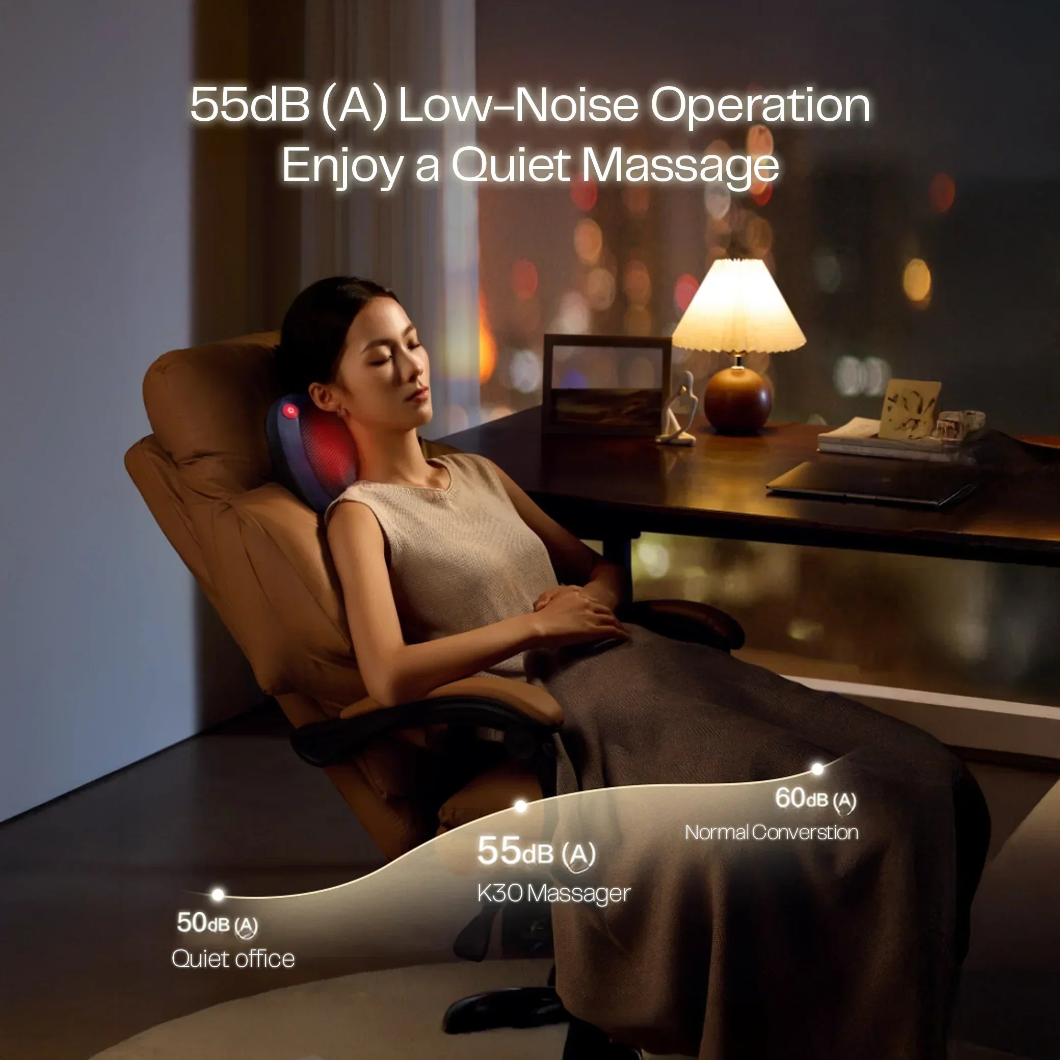 Woman using K30 massager on chair in quiet office with soft lamp light at night