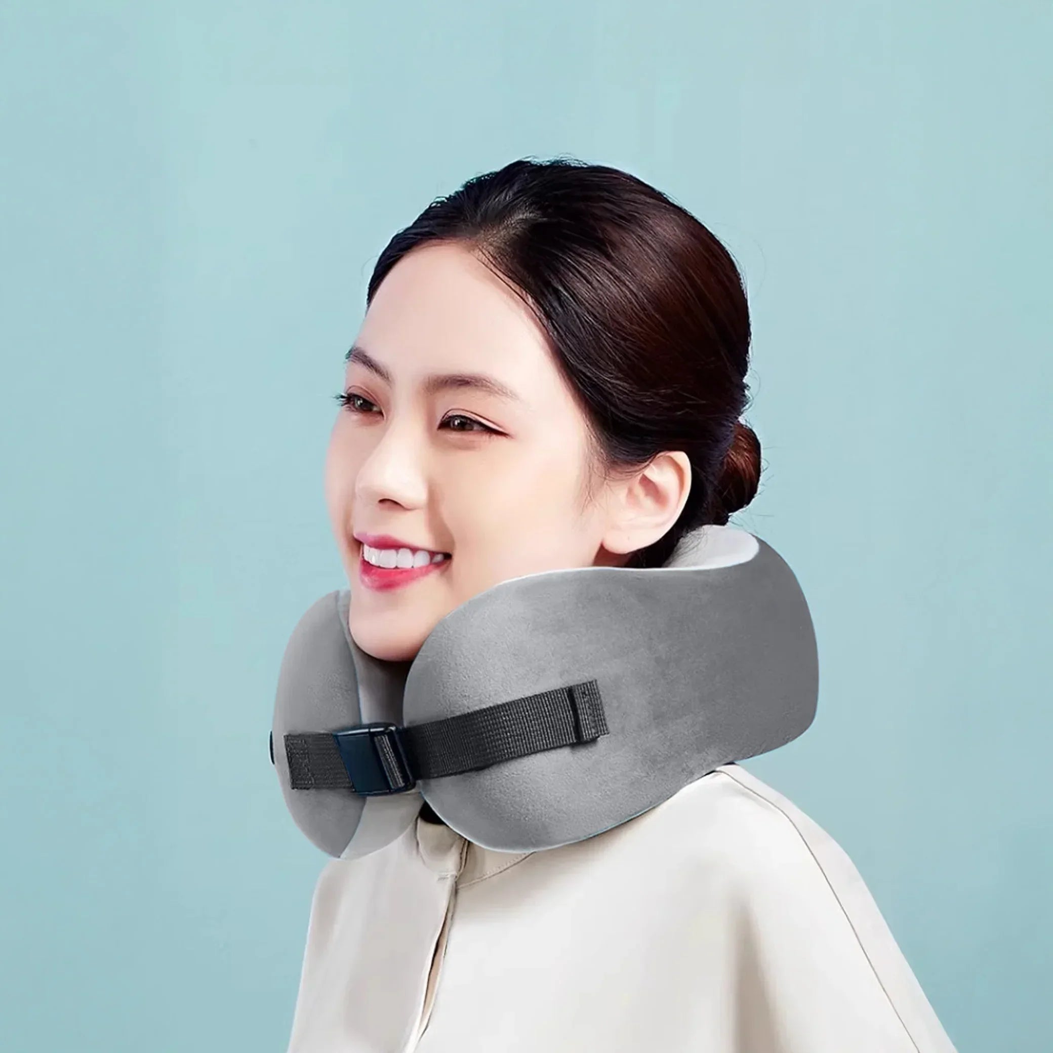 Woman wearing a gray portable massage neck pillow against a blue background