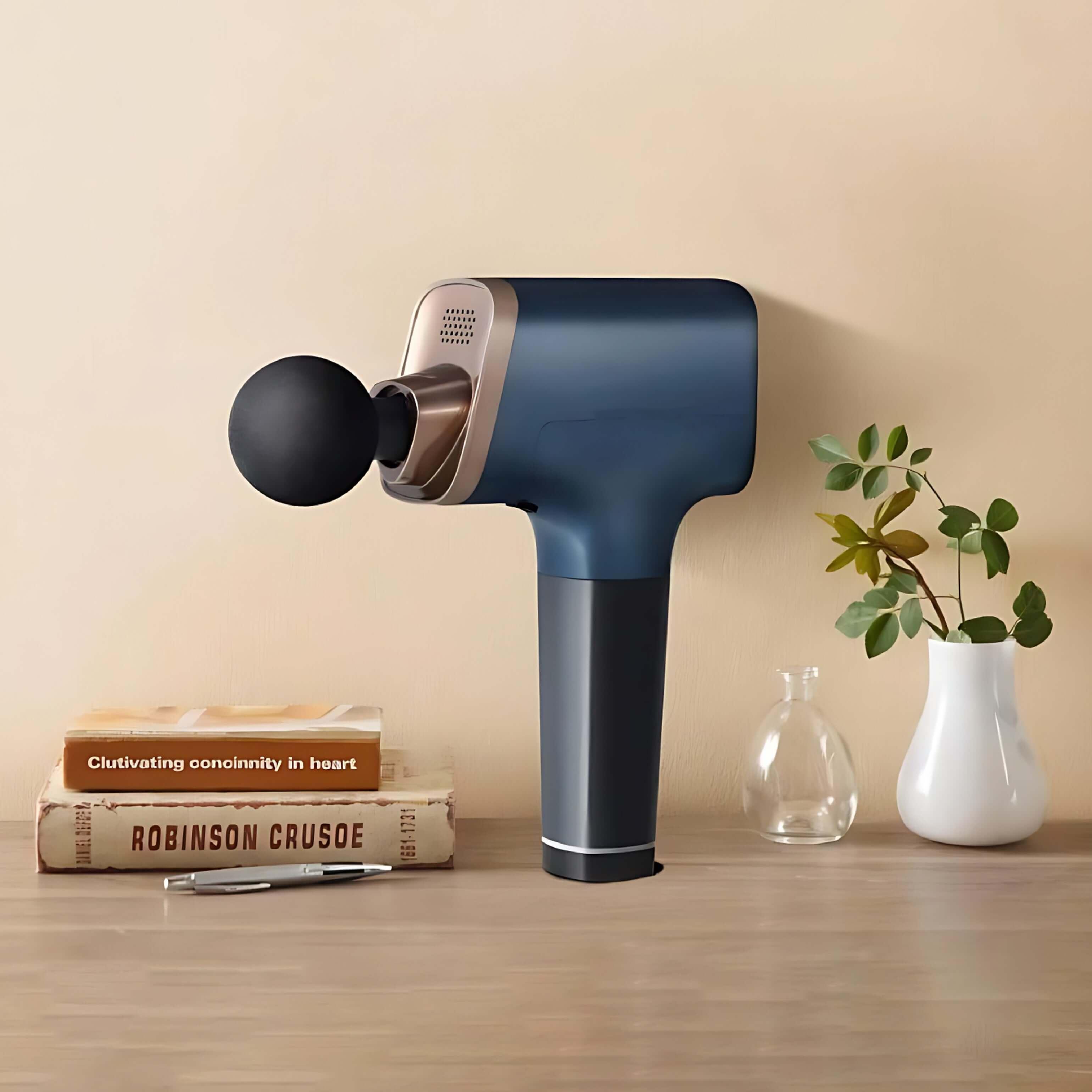 Dark blue handheld massage gun by Rotai, model RT1025, with replaceable massage heads placed on a wooden table near books and plants.