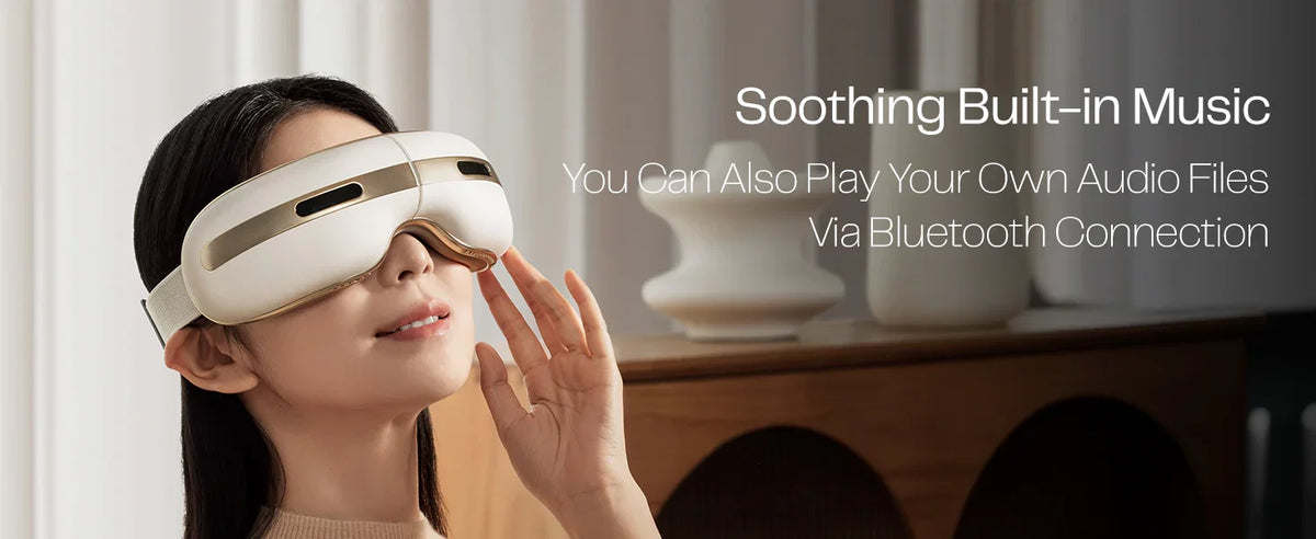 Woman wearing a white eye massager with Bluetooth audio in a modern living room setting