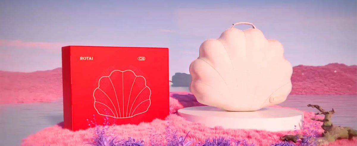 Shell-shaped portable massager and red packaging on pink landscape, relaxation product
